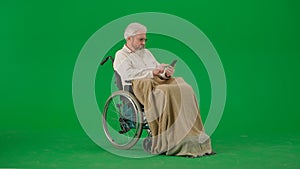 Portrait of aged man isolated on chroma key green screen background. Senior man in wheelchair covered by plaid swiping