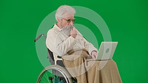 Portrait of aged man isolated on chroma key green screen background. Senior man in wheelchair covered by plaid watching