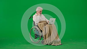 Portrait of aged man isolated on chroma key green screen background. Senior man in wheelchair covered by plaid watching