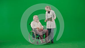 Portrait of aged man isolated on chroma key green screen background. Senior man in wheelchair talking with female doctor