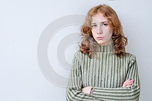 Portrait of aggravated sad woman with long red hair with crossed hands expressing her dissatisfaction and disconent.