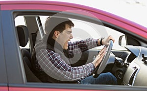 Portrait of aggressive male driver honking in traffic jam