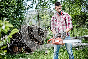 Portrait of aggressive, muscular and athletic man with chainsaw