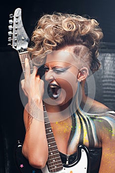 Portrait of aggressive screaming punk with guitar