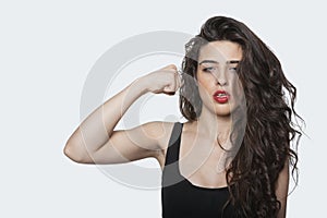 Portrait of an aggressive woman with punching gesture over gray background