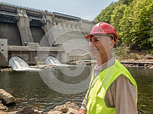 Portrait of an aging worker in a helmet against the backdrop of hydroelectric turbines