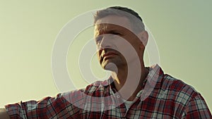 Portrait agronomist inspecting field in sunset sunlight. Tired farmer resting