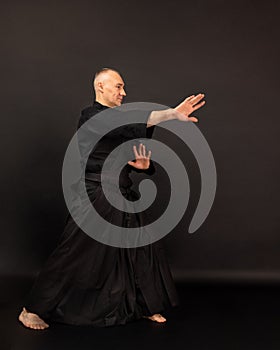 Portrait of aikido sensei master with black sensei belt in taekwondo kimono on black background. Traditional samurai