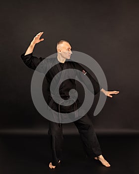 Portrait of aikido sensei master with black sensei belt in taekwondo kimono on black background. Traditional samurai hakama kimono