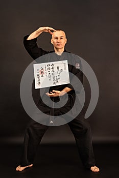 Portrait of aikido sensei master with black sensei belt in taekwondo kimono on black background. Traditional samurai hakama kimono