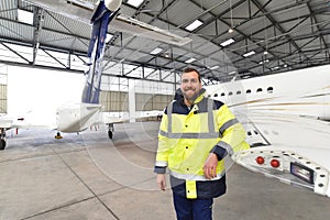 Portrait of an aircraft mechanic in a hangar with jets at the airport - Checking the aircraft for safety and technical function