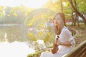 Portrait Aisan Chinese girl woman artist play violin in nature park forest enjoy leisure time performance outdoor lake bench