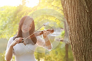 Portrait Aisan Chinese girl woman artist play violin in nature park forest enjoy leisure time performance outdoor lake sunrise