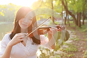 Portrait Aisan Chinese girl woman artist play violin in nature park forest enjoy leisure time performance outdoor lake sunset
