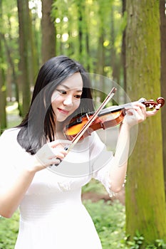 Portrait of Aisan Chinese girl woman artist play violin in nature park forest enjoy leisure time performance outdoor in park