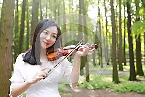 Portrait of Aisan Chinese girl woman artist play violin in nature park forest enjoy leisure time performance outdoor park sunshine