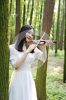 Portrait of Aisan Chinese girl woman artist play violin in nature park forest enjoy leisure time performance outdoor park sunshine