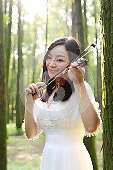 Portrait of Aisan Chinese girl woman artist play violin in nature park forest enjoy leisure time performance outdoor park sunshine