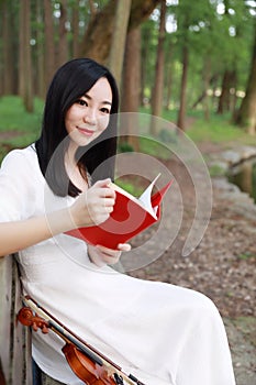Portrait Aisan Chinese girl woman artist read book on a bench knowledge hobby violin free causal way of life park garden forest