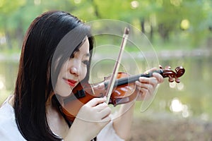 Portrait of Aisan Chinese girl woman play violin in nature park by lake sunset enjoy leisure time performance outdoor in park