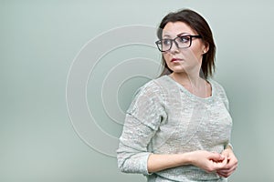 Portrait of alone sad mature woman with glasses on green background