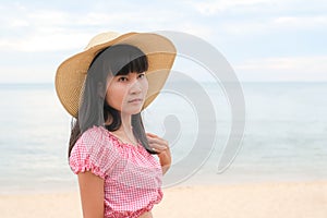 Portrait alone woman standing at coast with hat on blur blue sea and blue sky.