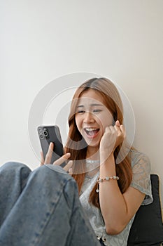 Portrait of an Amazed Asian girl receiving unexpected news through her smartphone