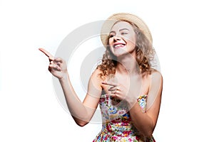 Portrait of an amazed cute girl in summer clothes pointing away at copy space with two fingers isolated over white background