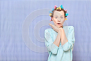 Portrait of amazed girl with bright colorful hair curlers on head