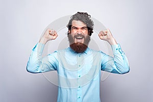 Portrait of amazed and happy man in blue shirt celebrating victory. GOAL