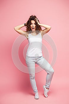 Portrait of amazed young woman over pink background.