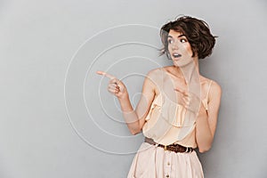 Portrait of an amazed young woman pointing fingers away