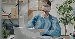 Portrait of ambitious businessman using laptop and typing working in office alone