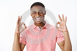 Portrait of ambitious good-looking african american young positive guy showing okay gesture with both hands and smiling