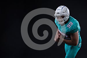 Portrait of American football player holding a ball in both his arms. Copy space. Rugby