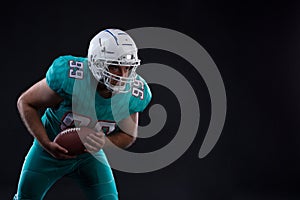 Portrait of American football player holding a ball in both his arms. Copy space. Rugby