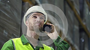 Portrait of american man talking on phone standing in warehouse during working day.