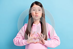 Portrait of amorous girl sending air kiss showing heart shape isolated over bright blue color background