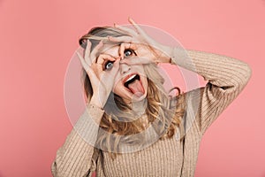 Portrait of amusing woman sticking out tongue and having fun isolated over pink background