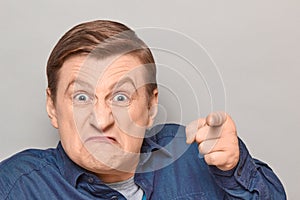 Portrait of angry annoyed man with pointing with index finger at you