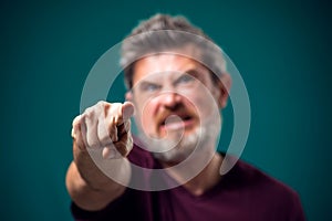 A portrait of angry bearded man pointing finger at camera. People and emotions concept