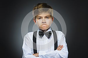 Portrait of angry boy on gray background. Negative human emotion, facial expression. Closeup