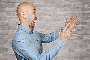 Portrait angry dangerous bald man trying to watch and scare on white brick wall background