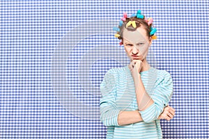 Portrait of angry disgruntled girl with colorful hair curlers on head