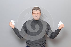 Portrait of angry furious man holding crumpled pieces of torn paper