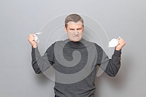 Portrait of angry furious man holding crumpled pieces of torn paper