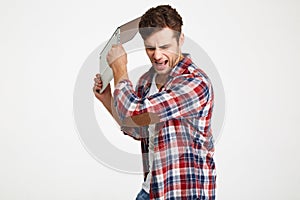 Portrait of an angry furious man throwing his laptop computer