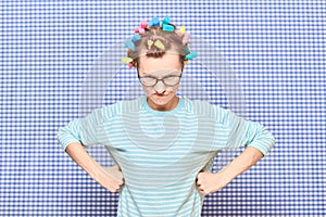 Portrait of angry girl with colorful hair curlers on her head