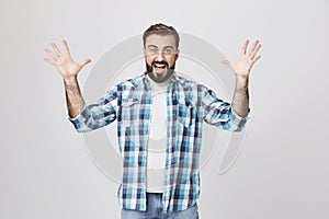 Portrait of angry insane european man, shouting and spreading his hands while gesturing, over gray background. I
