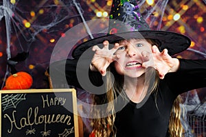 Portrait of an angry little girl in a witch costume, on Halloween background.